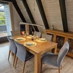Esszimmer mit Holztisch, grauen Stühlen und Kamin. Durchgang zur Terrasse.