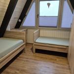 Zwei Schlafplätze in einem Dachzimmer mit Holzboden und Dachfenster.