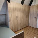 Schlafzimmer mit Holzschrank, Tür und Wandbild