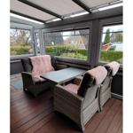 Terrasse mit Sitzgruppe, Tisch und Fenstern. Holzdecke und Außenausstattung.