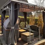 Terrasse mit Pavillon, Sitzgruppe und Grill unter schattigem Dach.