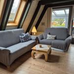Zwei graue Sofas mit Kissen stehen vor großen Fenstern und einer Tür.