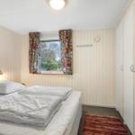 Bedroom with bed, window, and curtains. Wall art and coat rack are visible.