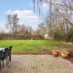 Patio with table and chairs, view of green lawn and trees.