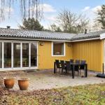 Yellow house with terrace, table, and chairs. Backyard with trees and plants.