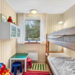 A bedroom with bunk beds, toys, and a window overlooking greenery.