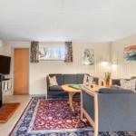 Living room with fireplace, sofa, table, and rug. Windows with curtains and wall art.