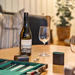 On the table is a wine bottle, a wine glass, and a backgammon set.