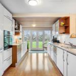 Kitchen with white cabinets, granite countertop, and view of the garden.