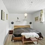 Bedroom with bed, window, wall mirrors, and wooden floor.