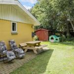 Yellow house with seating and picnic table in garden. Backyard with playhouse and shed.