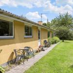 Yellow house with terrace, garden, and seating areas under blue sky.