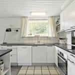 Kitchen with white cabinets, black countertops, and window with view of greenery.