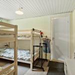 Room with two bunk beds, coat rack, and window with view of greenery.