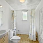 Bathroom with shower, toilet, and sink. Tile floor and window.
