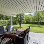 Patio with table and chairs, view of green lawn and trees.