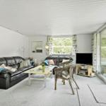 Living room with leather sofa, coffee table, and TV. Entrance to terrace with seating area.