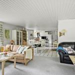 Living and dining area with kitchen, sofa, and view of the garden.