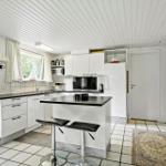 Kitchen with white cabinetry, black countertops, and bar stools.