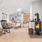 Living room with fireplace, chairs, and wall decor. Passage to bedroom.