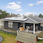 A dark house with solar panels, a terrace, and a trampoline in the garden.