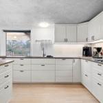 Kitchen with white cabinets, wooden countertops, and windows to the garden.