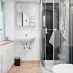 Bathroom with shower, sink, and toilet. Window and mirror visible.