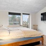 Bedroom with bed, windows, and TV mounted on the wall.