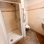 Badezimmer mit Dusche, Toilette und Waschbecken.