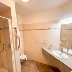 Badezimmer mit Dusche, Toilette und Waschbecken mit Spiegel.