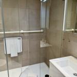 Badezimmer mit Dusche, Waschbecken und Handlauf.