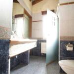 Badezimmer mit Waschtisch, Toilette und Dusche. Wandfliesen und Mosaikverzierung.