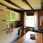 Kitchen with dining area, wooden walls, window, and modern built-in kitchen.