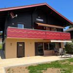 Two-story house with balcony, terrace, and garden. Door with inscription Home.