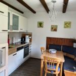 Kitchen with dining area, wooden beams, white cabinets, and kitchen counter.