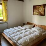 Bedroom with wooden bed, window, and painting on the wall.