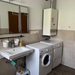 Laundry room with washing machine, dryer, and sink with mirror.