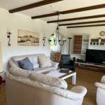 Living room with sofa, TV, and foosball table. Wooden beams on ceiling.