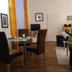Wohn- und Essbereich mit Glas-Tisch, Stühlen, Sofa und TV.