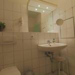Badezimmer mit Waschbecken, Spiegel, Toilette und Handtuchhalter.