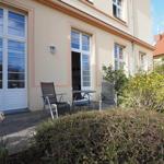 Terrasse mit zwei Stühlen und Tisch vor einem Haus mit Fenstern.