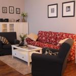 Wohnzimmer mit rotem Sofa, zwei schwarzen Sesseln und weißem Couchtisch.
