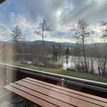 Terrace with table offers view of lake and hills.