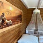 Bedroom with wooden walls, child bed with mosquito net, and oriental-style wall art.