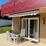 Terrace with table and chairs under awning. Sliding door leads into the house.