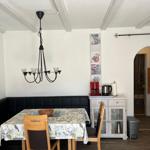 Dining area with table, chairs, and black bench under a hanging lamp.