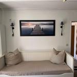 A sofa with cushions under a picture on the wall. A door leads into a hallway.