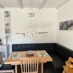 Dining area with wooden table, black bench, and modern pendant lamp.