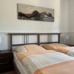 Two beds with colorful bedding and nightstands with lamps. Wall art above headboard.