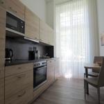 Küche mit Essbereich, Holzmöbeln und Fenster mit Vorhängen.